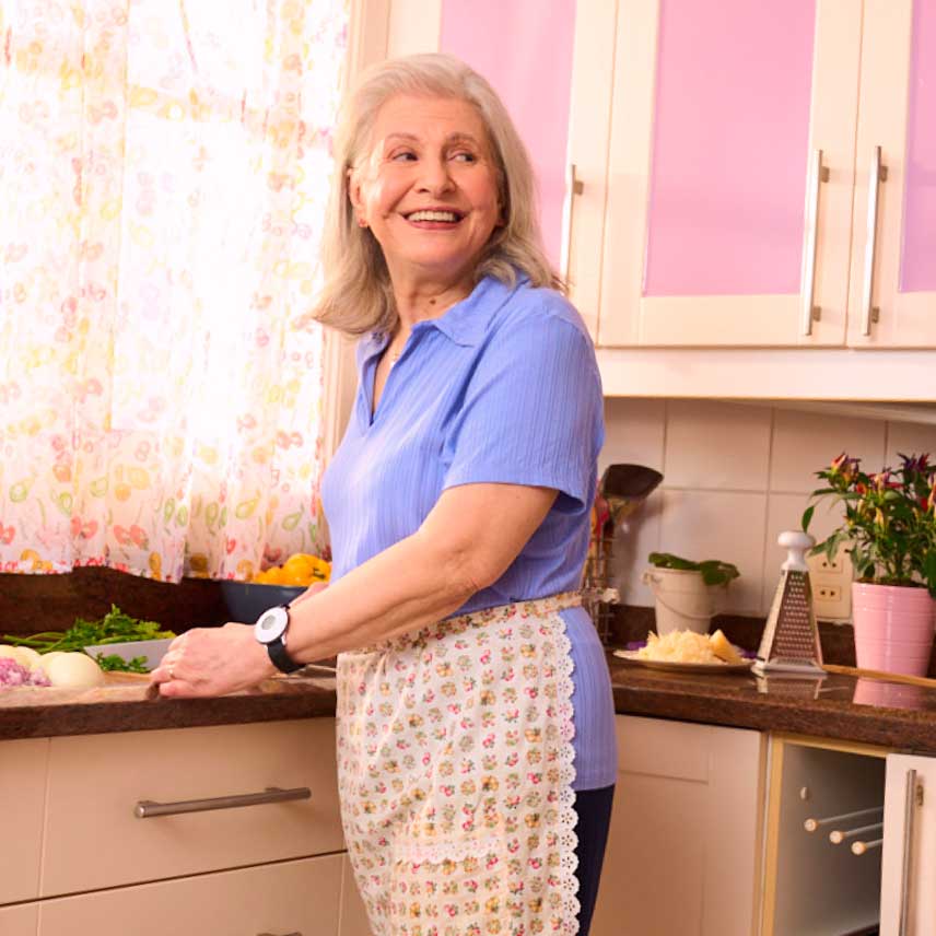 Helena (senhora de idade) sorrindo na cozinha.